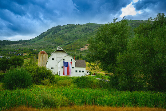 Classic Landmark Farmhouse with dramatic stormy clouds rising behind the Wasatch Mountain Range in the Historic Park City, Utah, USA