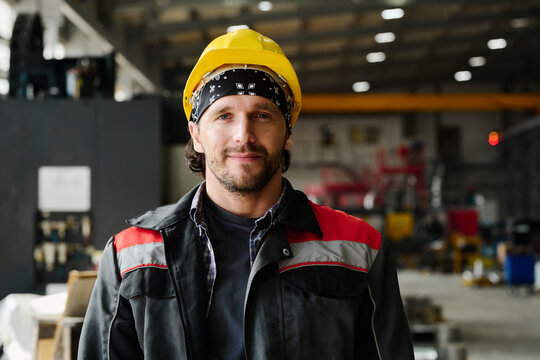 Portrait of smiling male worker with safety helmet in industrial setting smiling at camera
