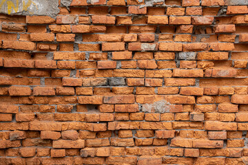 A red brick wall with a few missing bricks. The wall is old and has a rough texture.