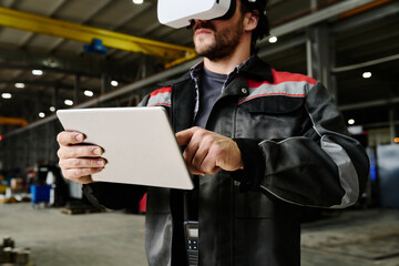 Man using virtual reality headset for training inside industrial warehouse Holding tablet