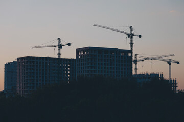 constructing buildings, block of flats. Construction of multi-storey buildings. Houses and construction cranes on sky background. Construction crane and building construction site