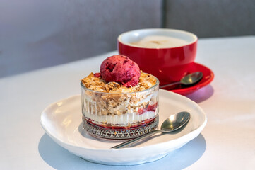 Millefeuille cake in a bowl with a scoop of berry sorbet and a cup of aromatic cappuccino coffee.