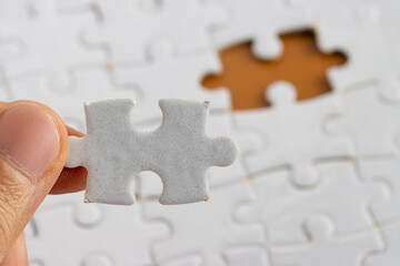 Hand holding a puzzle pieces, completing jigsaw puzzle. business concept. Selective focus.