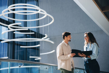 Successful business partners holding a copy of their agreement document in a convention center