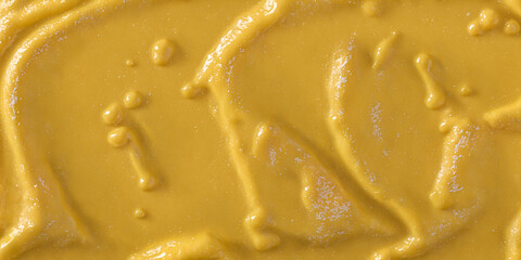 Yellow mustard sauce or paint, delicious yellow creme, smooth and wavy. Food background, texture, wallpaper or banner.