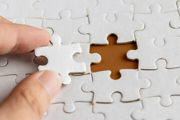 Obraz premium Hand holding a puzzle pieces, completing jigsaw puzzle. business concept. Selective focus.