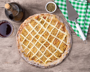 Chicken and Catupiry cream cheese pizza over wooden table with wine