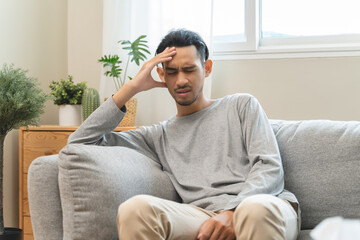 Guy have headache and dizzy sitting on sofa at home
