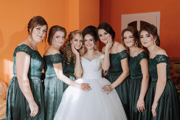 A group of women are posing for a picture, with one of them wearing a white dress. Scene is happy and celebratory