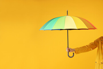 Woman with colorful umbrella on yellow background, closeup. Space for text