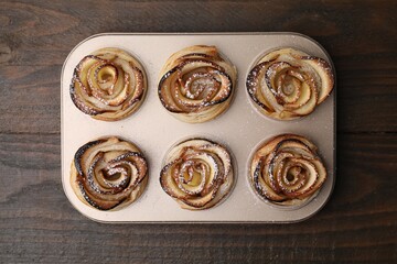 Freshly baked apple roses on wooden table, top view. Puff pastry