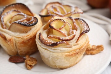 Freshly baked apple roses and walnuts on table, closeup. Puff pastry