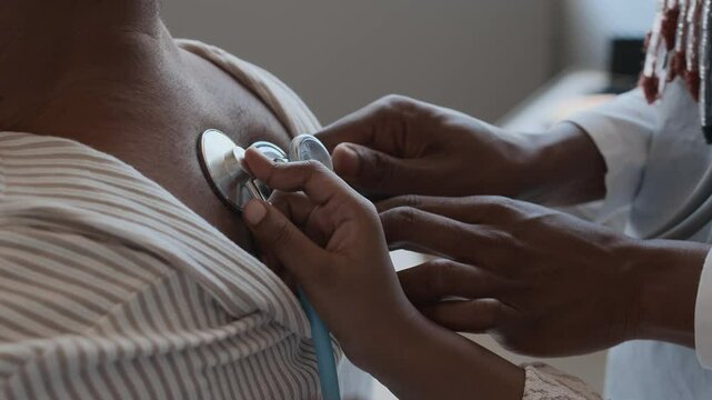 Close up shot of unrecognisable female doctor putting stethoscope on mans upper back, unknown child copying her using another device
