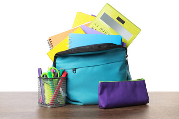 Backpack with different school stationery on wooden table against white background