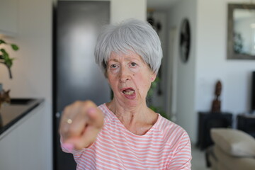 Senior woman accusing someone of doing something wrong with hand gesture 