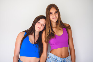 portrait of two 14 years old best friends girls close to a wall with color shirt