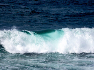 A gentle wave rolls in turquoise waters, capturing the serene and peaceful rhythm of the ocean against a calm backdrop.