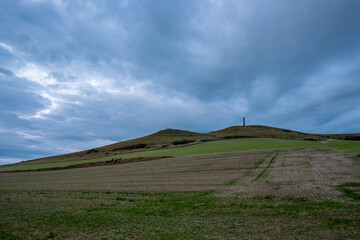 A beautiful scene of rolling hills beneath a dramatic sky filled with thick clouds during the...