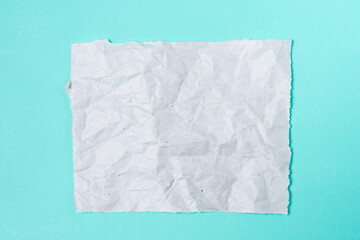 Crumpled paper to write a note on a turquoise background.