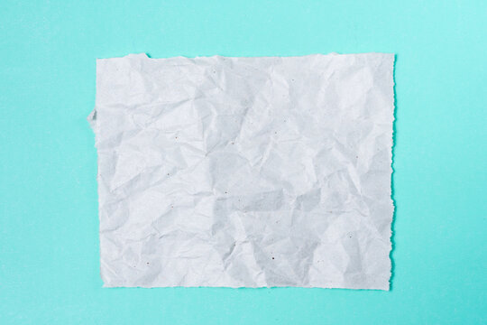 Crumpled paper to write a note on a turquoise background.