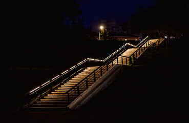 A brightly lit staircase in the darkness of night. Concrete illuminated staircase.