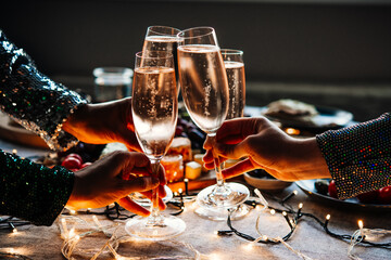 Friends celebrating Christmas or New Year eve party with champagne or sparkling wine.