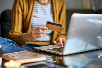 Fototapeta premium A person shopping online using a credit card while sitting comfortably on a couch in a cozy living room