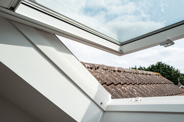 Obraz premium Newly installed skylight window seen opened in a first floor bedroom window of a converted bungalow. The window is opened to aid ventilation in the bedroom.