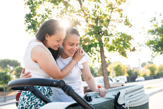 Lesbian couple admiring their son in a stroller at the park