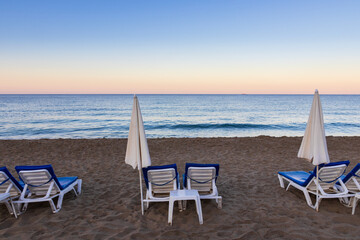 Sun umbrella and lounger on sand Kleopatra beach with sea at morning, Alanya