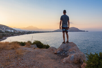 Man from back standing on rock, looking city Alanya, Turkey