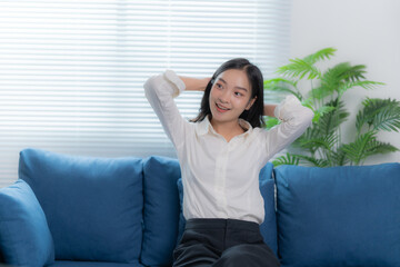 Happy Asian women sitting on the sofa working at home by used laptop and smartphone 