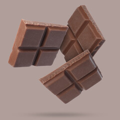 Pieces of sweet chocolate falling on color background
