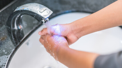 Close-Up of Hands of Young Student Using Automatic Faucet to Wash