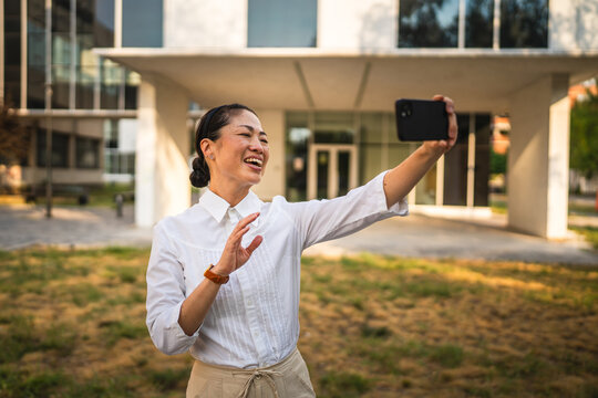 japanese woman stand in front buildings and have video call