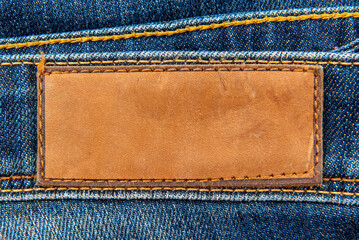 Empty worn leather patch on blue jeans. Empty space for writing. Blank leather jeans label