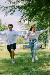 Fototapeta premium Loving couple of young girl and man are walking and having fun in park on warm summer day. Vertical photo. High quality photo