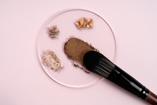 Top view of cosmetics and brush on pink background