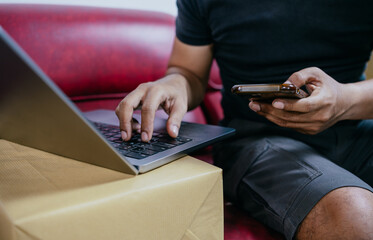 Start SME, small business entrepreneurs, SMEs of freelancers. Close-up shots of Asian man using smart phone and laptop with boxes. Online Marketing and SME Delivery Ideas.