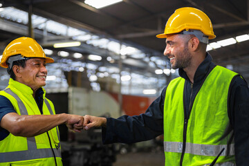 Two men in yellow safety gear shake hands