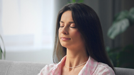 Young woman relaxing on couch with eyes closed