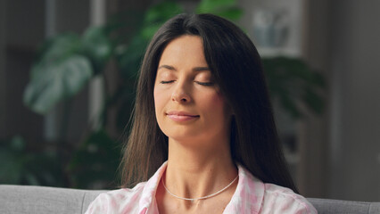 Serene woman relaxing with eyes closed at home