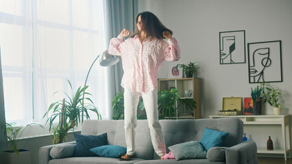 Young woman is dancing on the couch at home