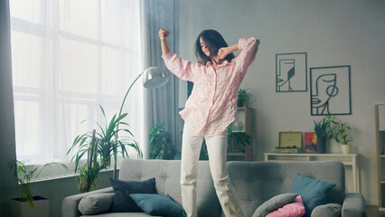 Carefree woman dancing on the couch at home,