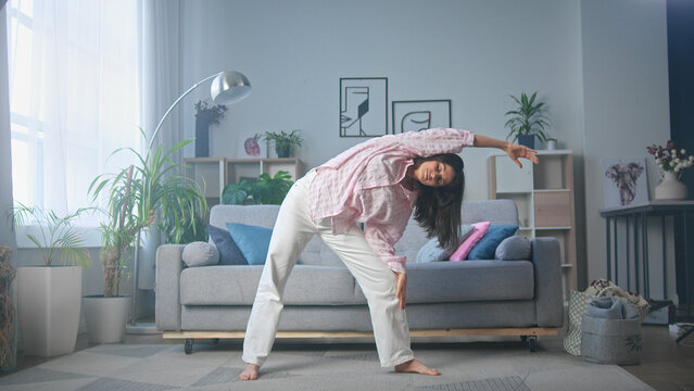 Young woman stretching body at home in living room