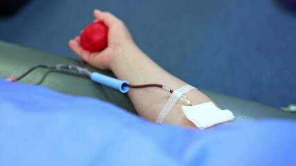 Arm of a person donating blood. A catheter is attached to the forearm filled with blood. Close up. - Powered by Adobe