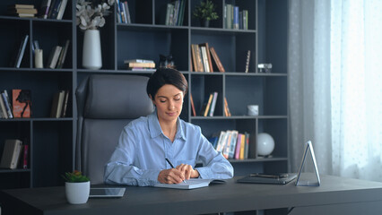 Businesswoman writing in notebook working at home