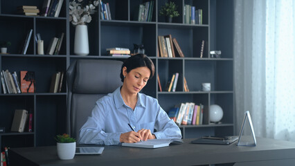 Businesswoman writing in notepad working at office