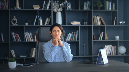 Businesswoman sitting at desk and thinking in