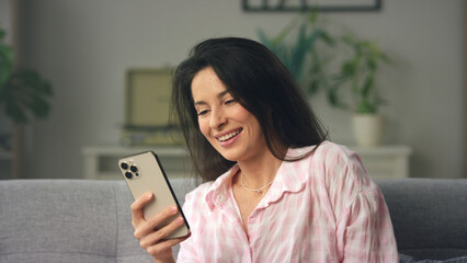 Woman relaxing on sofa browsing social media on